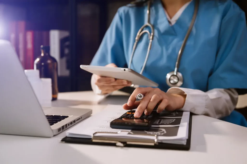 Doctor at desk with computer ipad calculator