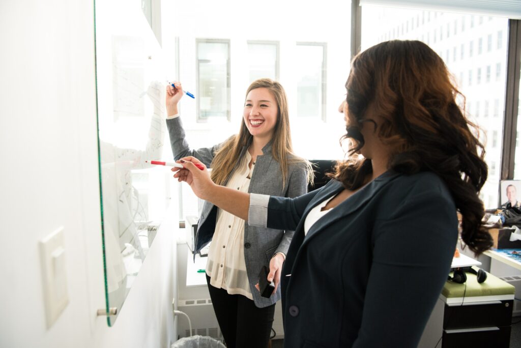 two women drawing on a whiteboard