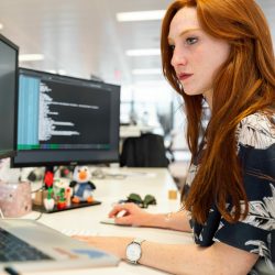 woman with red hair looking at a computer monitor